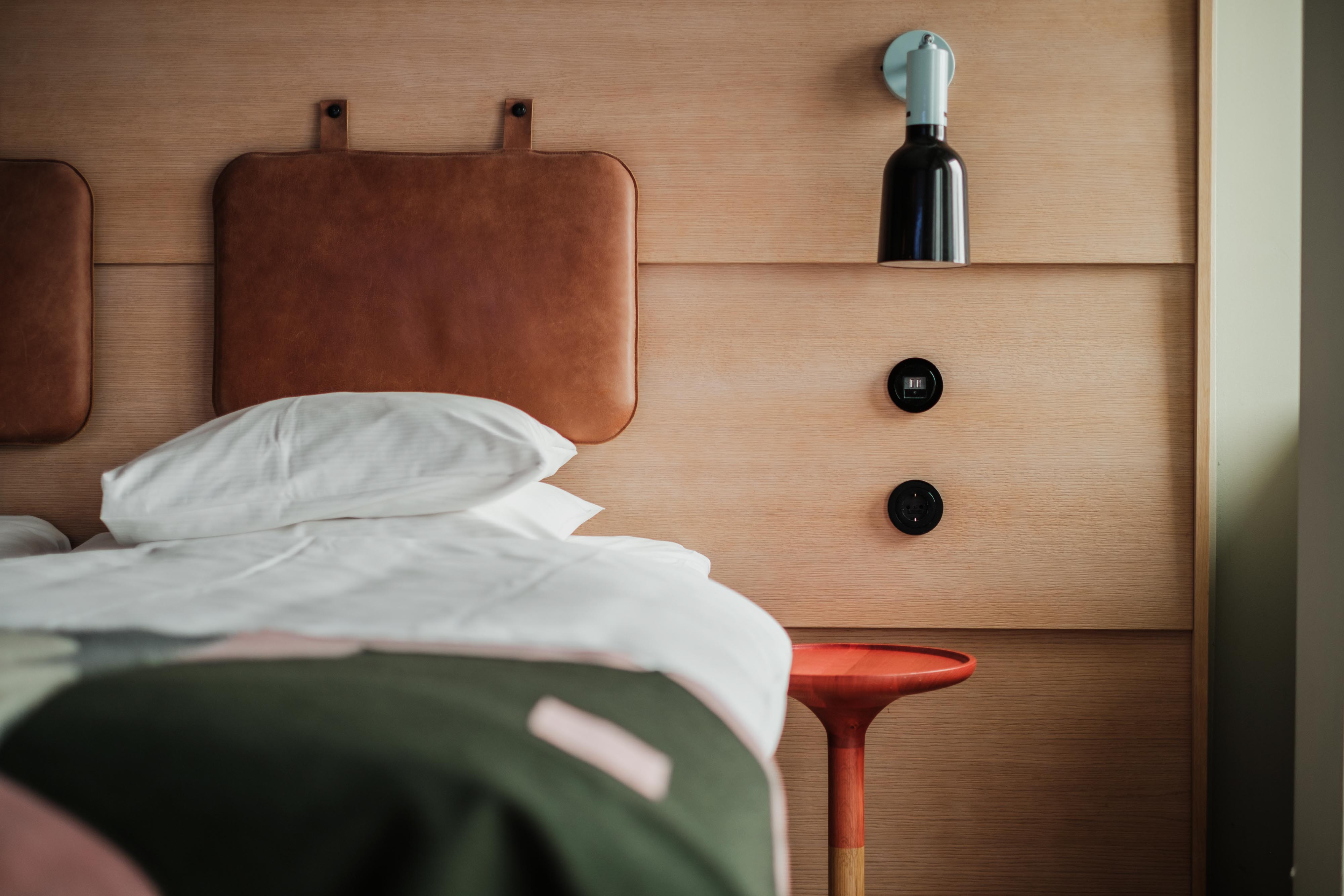 Standardrum på Hobo Hotel i centrala Stockholm med två enkelsängar, modernt rött sängbord och ljus träpanel bakom sängarna.