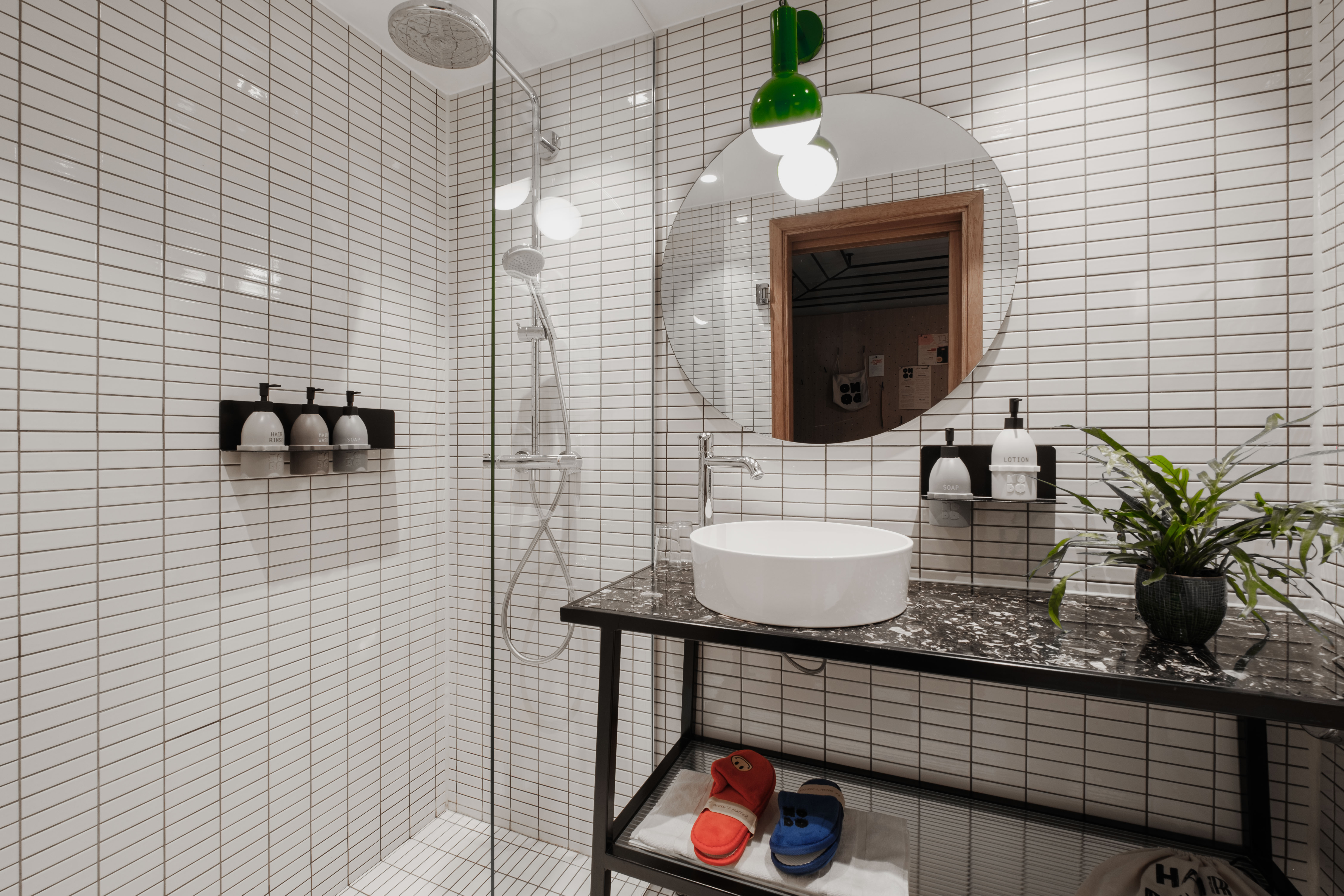 Spacious bathroom in a Sleeper room at Hobo Hotel in central Stockholm, featuring a shower with toiletries, and a modern, functional and stylish design with an urban feel and white tiling.