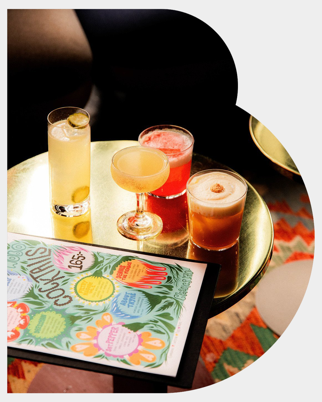 Several drinks in different colors and shapes on a round table in the lobby bar at Hobo Hotel in central Stockholm, along with a colorful menu.