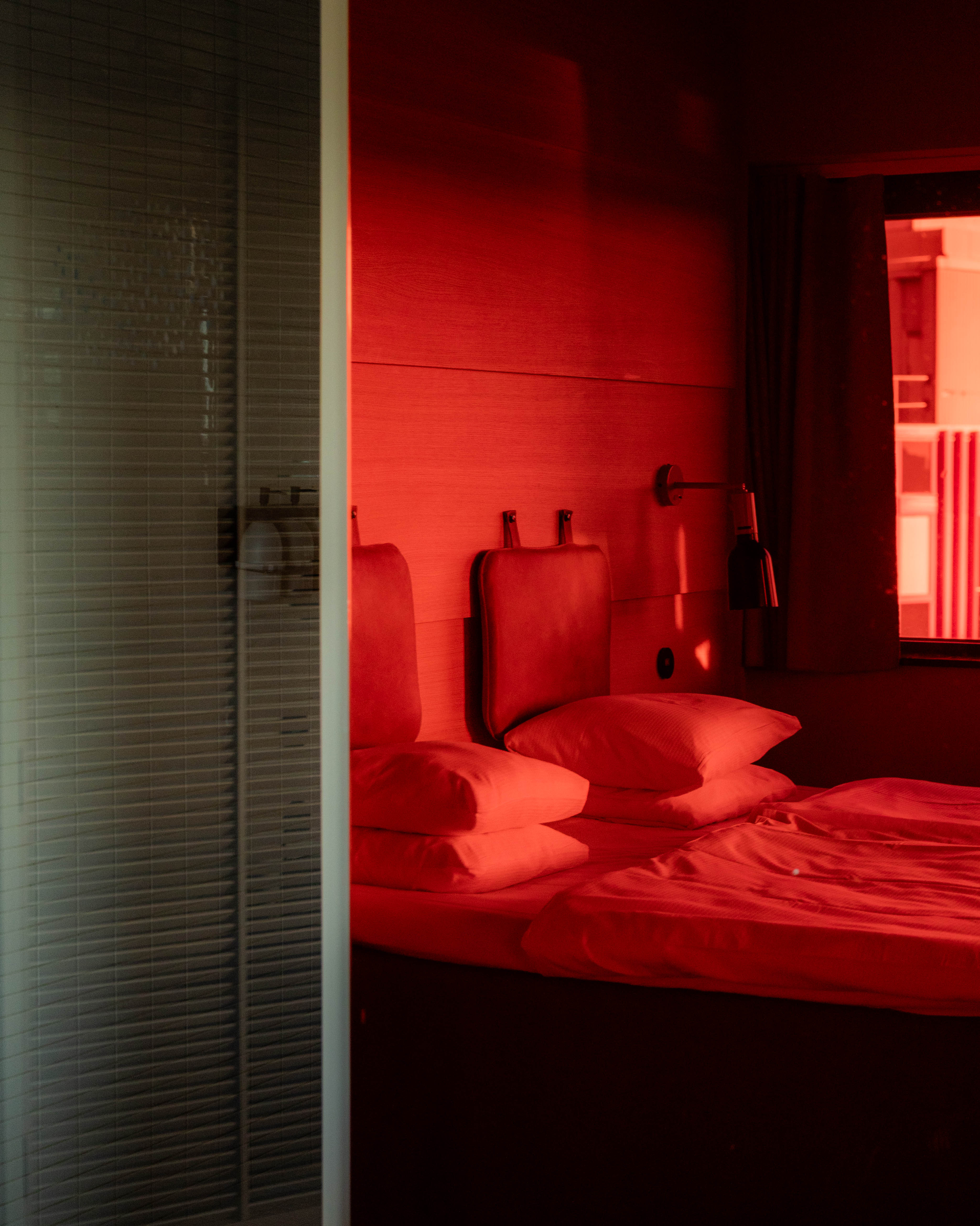 Image from a superior room at Hobo Hotel in central Stockholm where half of the image shows the bed reflected in a red mirror and the other half shows the spacious shower.