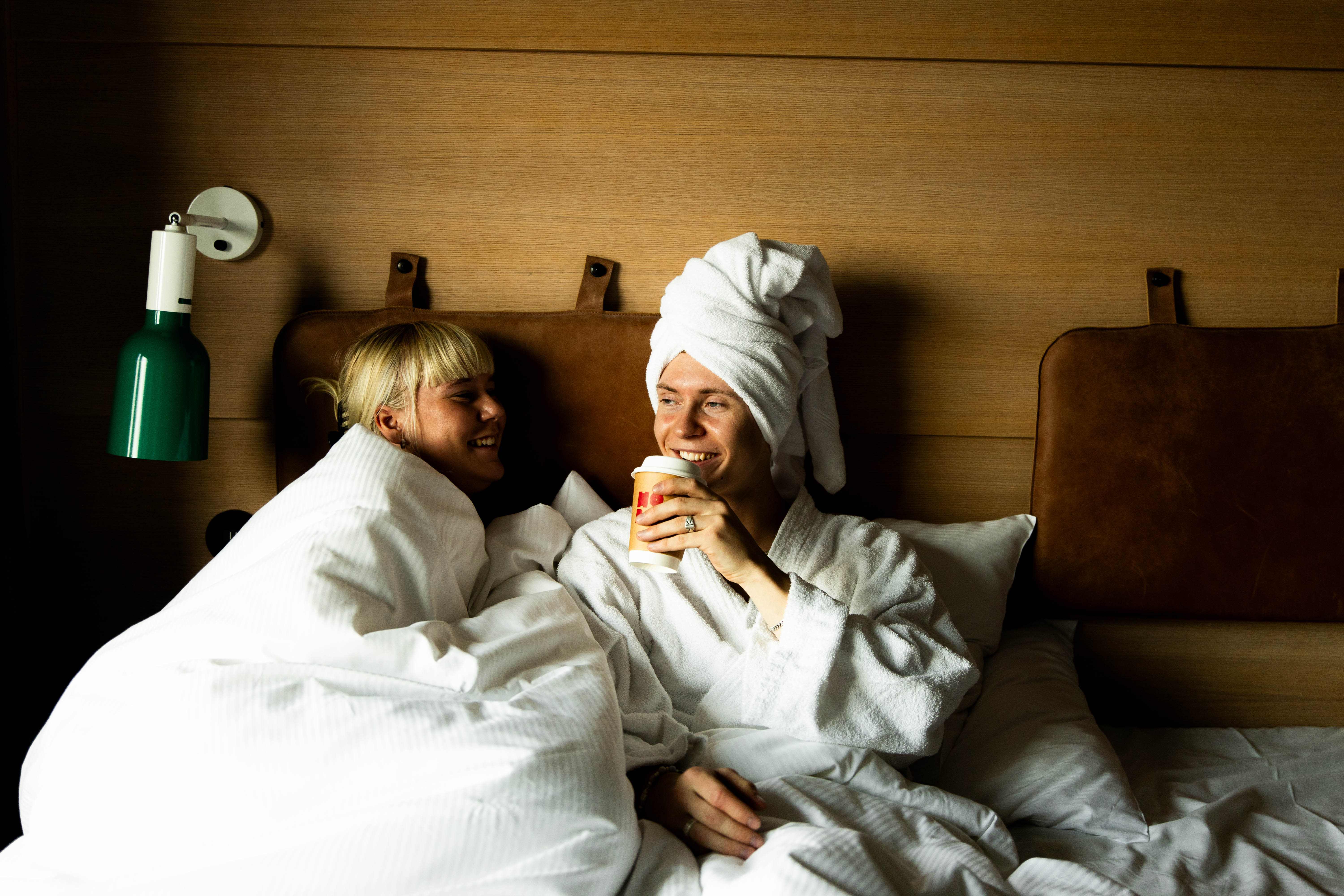 Two people relaxing in bed at Hobo Hotel in central Stockholm, wearing bathrobes and enjoying coffee.